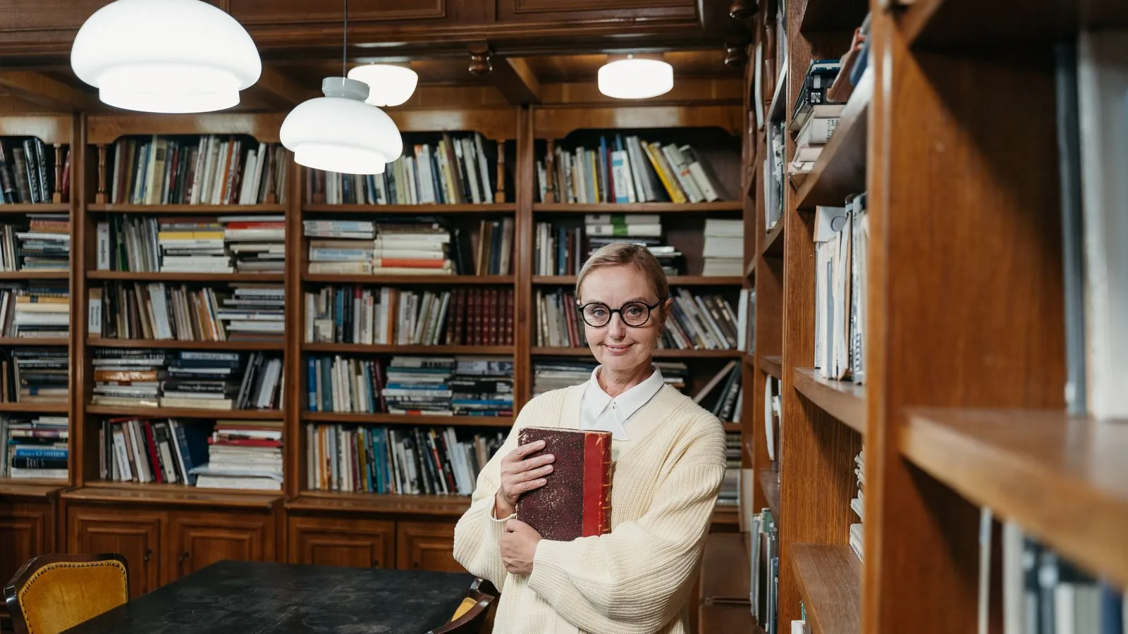 Mathilde, souriante, un livre relié dans les bras, au milieu de sa librairie